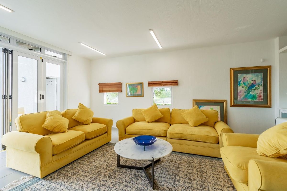 A bright and spacious living room featuring tiled flooring, recessed lighting, and bi-fold glass doors providing access to the outdoor area.