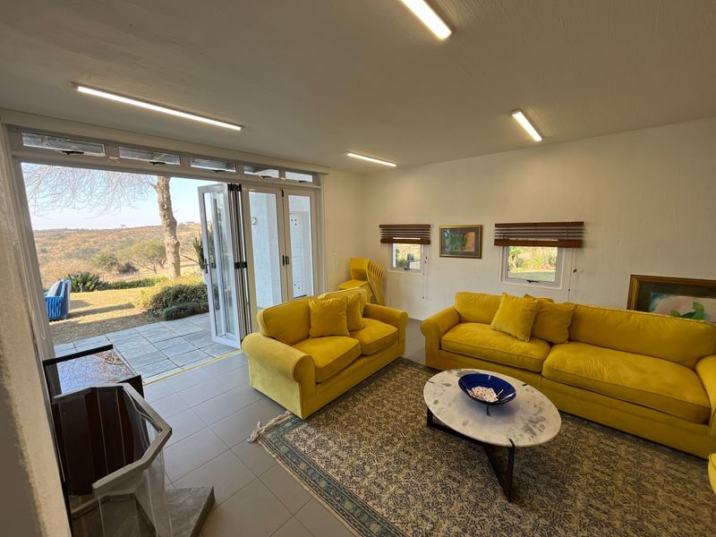 Spacious living room featuring tiled floors, a built-in fireplace, and large bi-fold doors opening to a scenic outdoor area.
