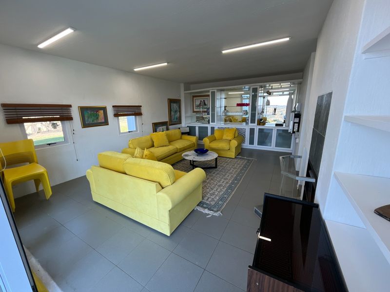 Spacious living room featuring tiled flooring, built-in display cabinetry, and ample natural light, offering a versatile layout for comfortable family living.