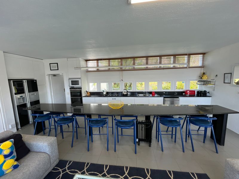 Spacious open-plan kitchen featuring a large central island with stone countertops, integrated appliances, and extensive cabinetry, seamlessly connecting to the living area.