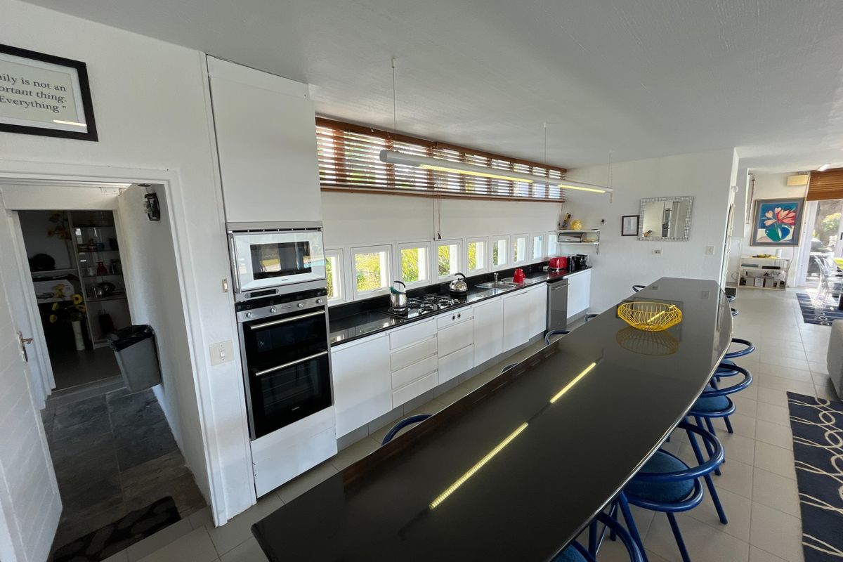 Modern kitchen featuring a long island with stone countertops, built-in oven, microwave, gas hob, and ample cabinetry, seamlessly connected to the living area.