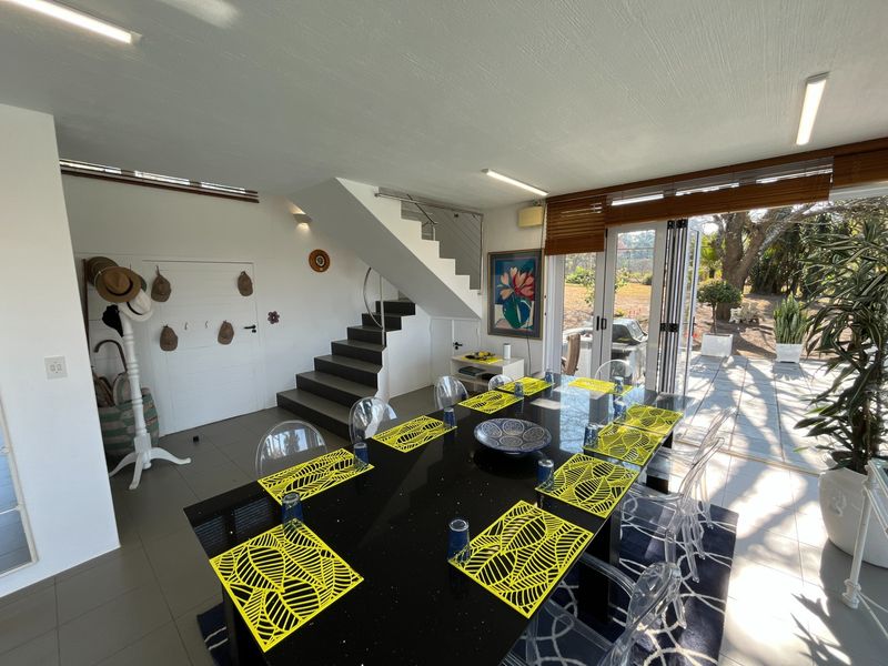 Bright dining area featuring modern tiled flooring, a staircase, and large folding glass doors that provide seamless access to the outdoor patio area.