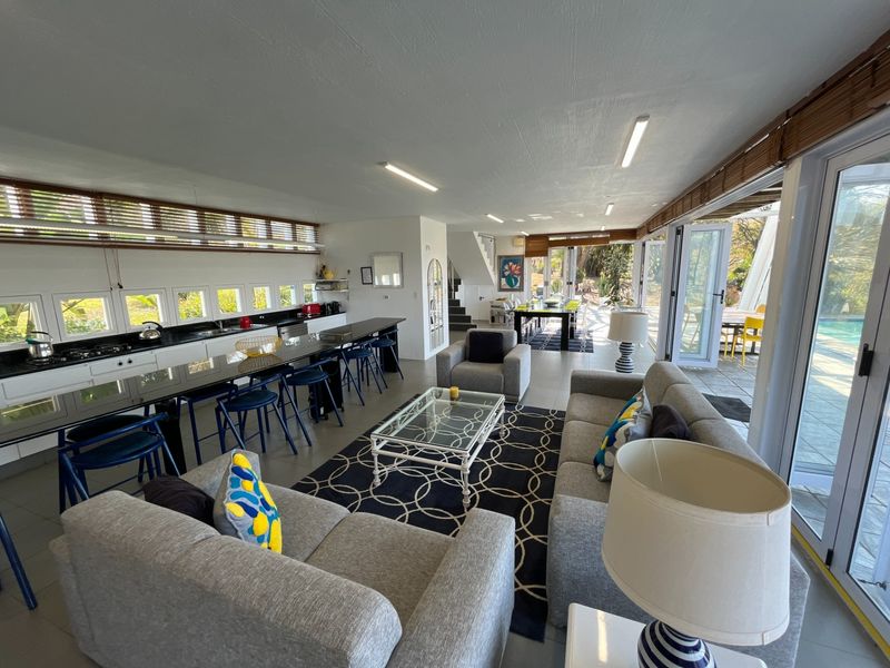 Spacious open-plan living area featuring a modern kitchen with a large island, seamless flow to the outdoor patio through bifold doors, and abundant natural light.