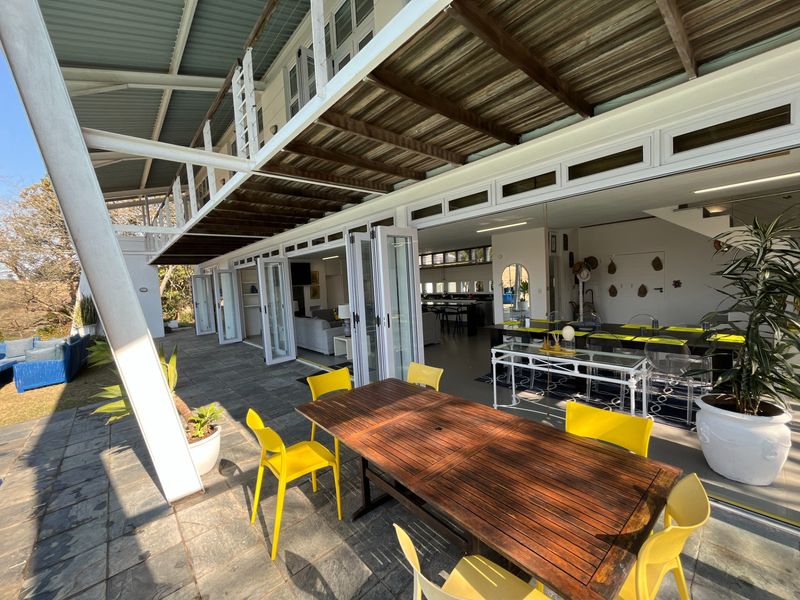 Spacious covered patio featuring slate flooring, exposed steel beams, and large bi-fold doors providing seamless indoor-outdoor flow to the main living area.