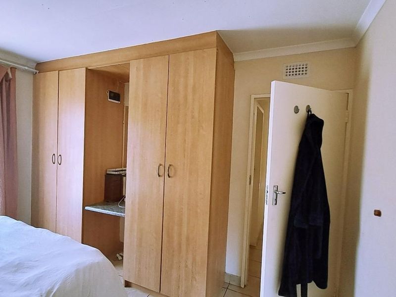 Bedroom featuring light wood built-in wardrobes with an integrated vanity area and neutral wall finishes.