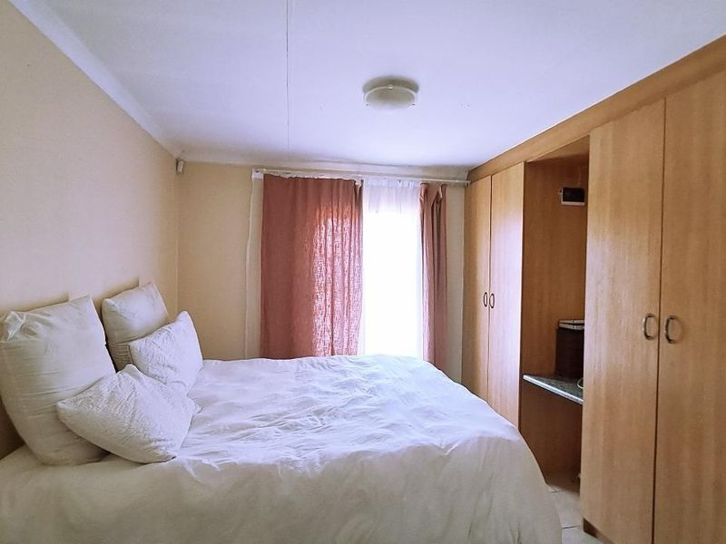 A bedroom featuring built-in wooden cupboards and natural light from a window.