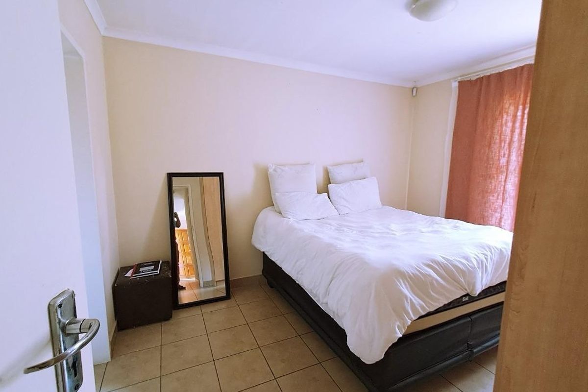 A standard bedroom featuring tiled flooring and neutral wall finishes, providing a functional and simple living space.