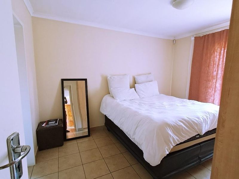 A standard bedroom featuring tiled flooring and neutral wall finishes, providing a functional and simple living space.