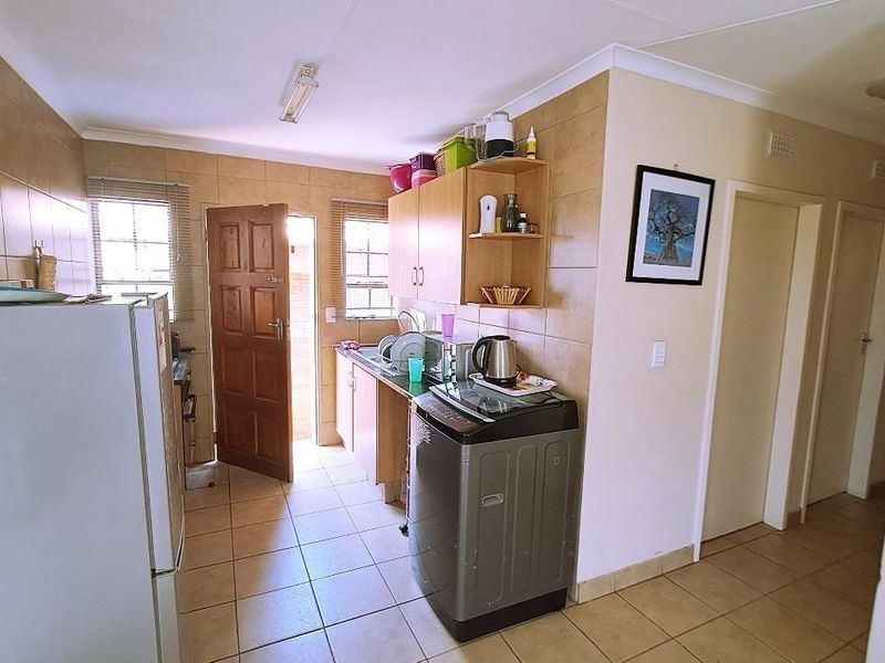 A functional kitchen featuring tiled walls and flooring, built-in cabinetry, and direct access to an exterior door.