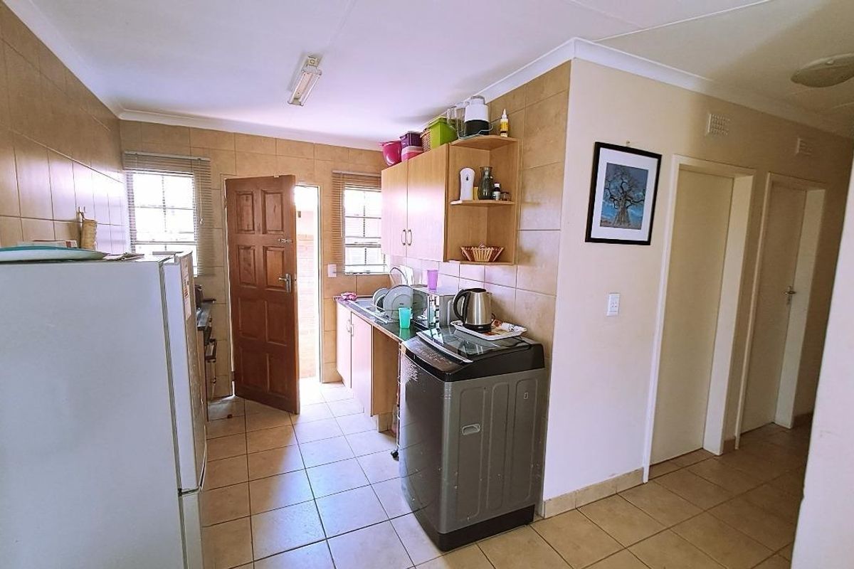 A functional kitchen featuring tiled walls and flooring, built-in cabinetry, and direct access to an exterior door.