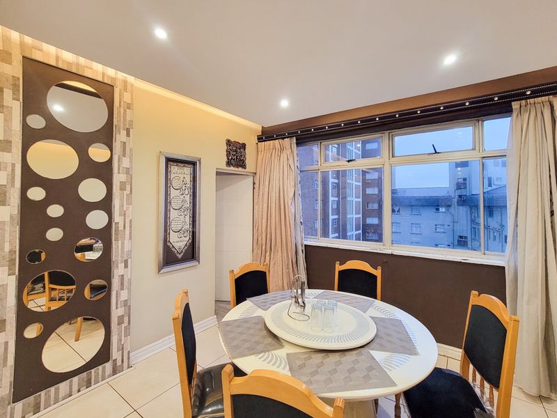 A well-lit dining area featuring tiled flooring, recessed ceiling lights, and decorative wall accents, offering a functional space for meals.