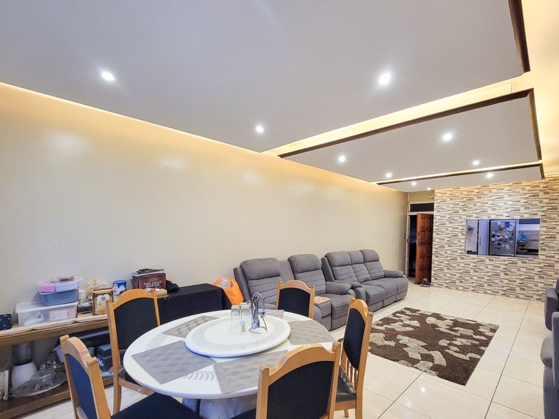 Open plan living and dining area featuring a modern dropped ceiling with recessed lighting and a decorative stone veneer feature wall.