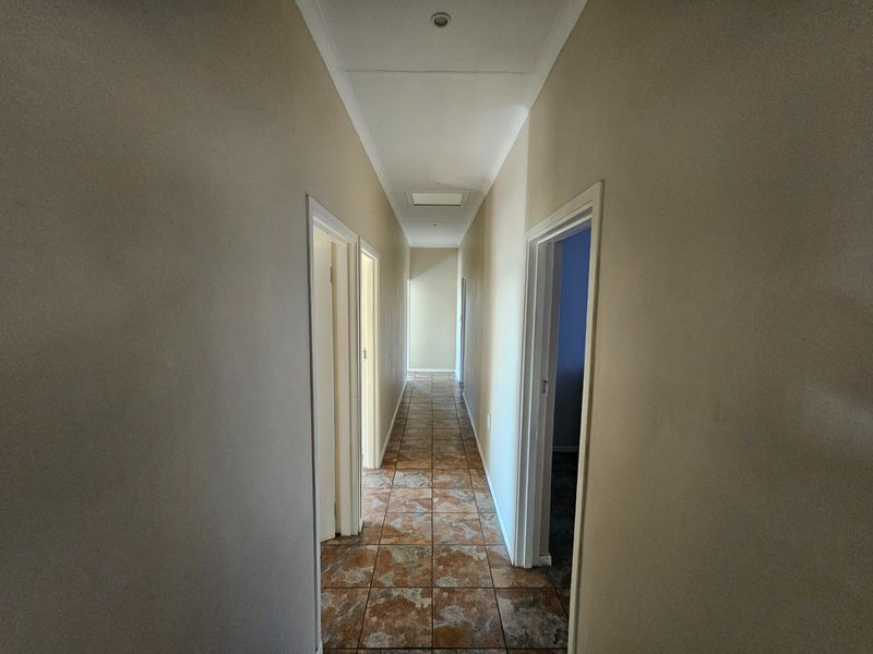 A clean, empty hallway featuring tiled flooring and recessed ceiling lighting, providing access to multiple rooms within the home.