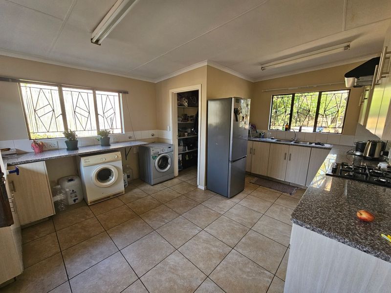 Spacious kitchen featuring granite countertops, built-in cabinetry, a gas hob, and an integrated laundry area with a convenient walk-in pantry.