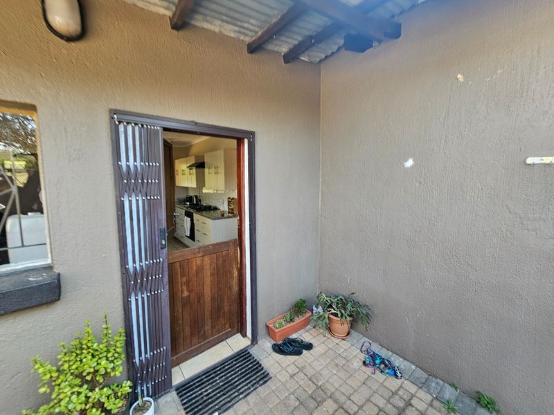 A covered patio area featuring a stable door entrance with a security gate, leading into the kitchen area.