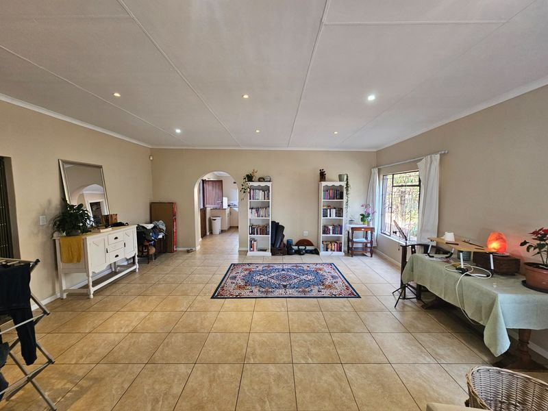 Spacious living area featuring neutral walls, tiled flooring, and recessed lighting, with an open archway leading to the kitchen area.
