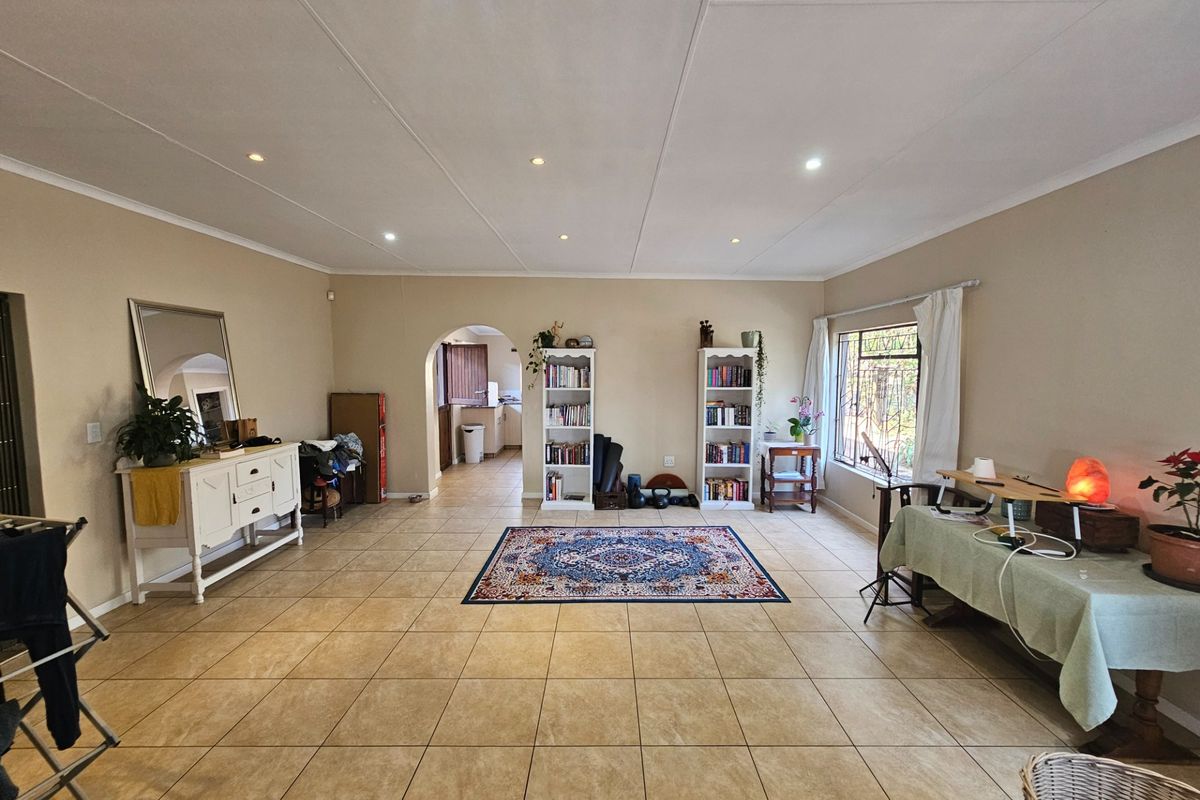 Spacious living area featuring neutral walls, tiled flooring, and recessed lighting, with an open archway leading to the kitchen area.