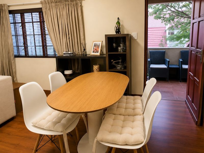 A well-lit dining area featuring laminate flooring and direct access to a private balcony through a sliding door.