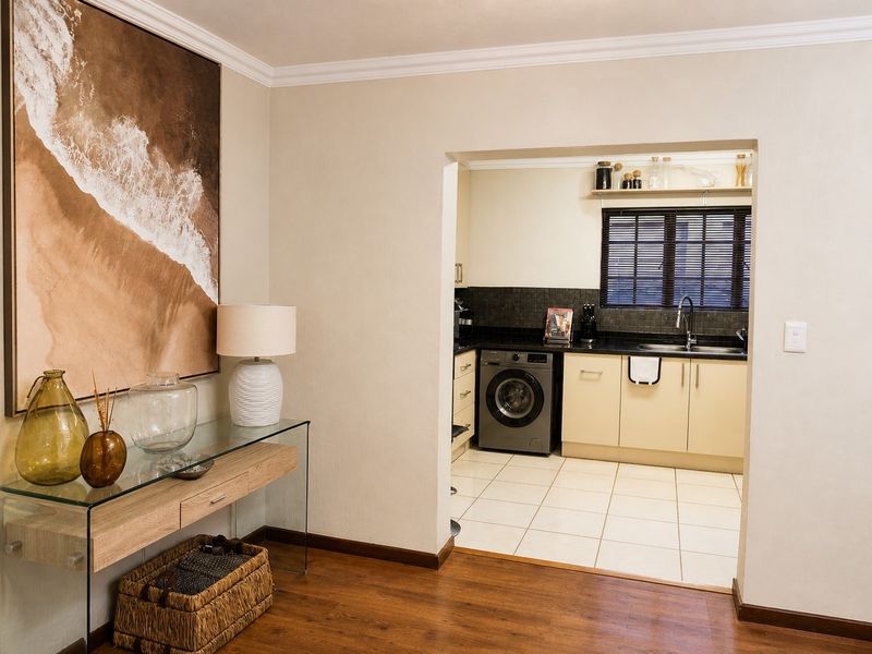 A functional kitchen featuring built-in cabinetry, tiled backsplash, and a stainless steel sink, seamlessly connected to the adjacent living area.