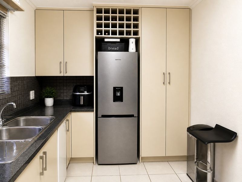 A functional kitchen featuring neutral laminate cabinetry, granite countertops, a double bowl stainless steel sink, and a built-in wine rack.