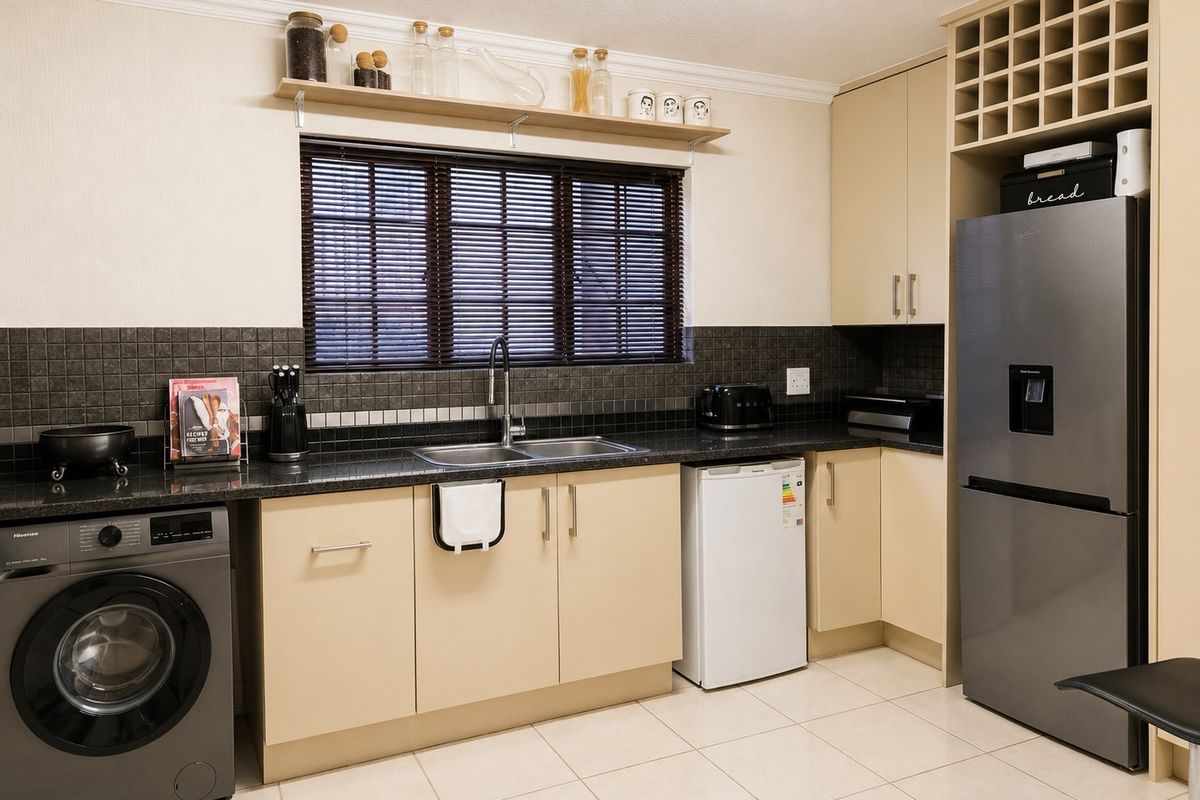 A well-maintained kitchen featuring neutral cabinetry, granite countertops, a tiled backsplash, and integrated space for laundry and refrigeration appliances.