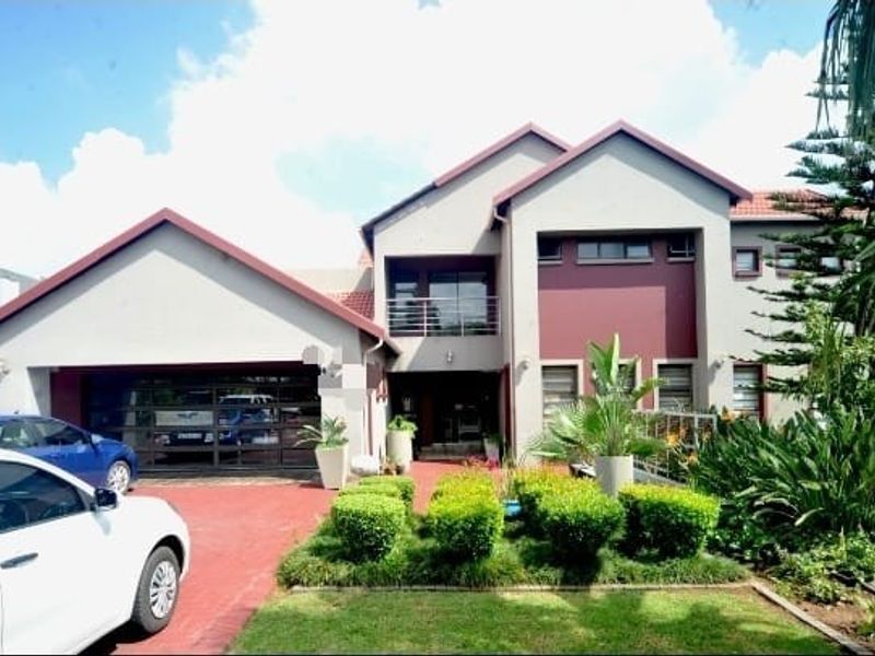 Front elevation of a two-story residential property featuring a paved driveway, double garage, and landscaped garden area.