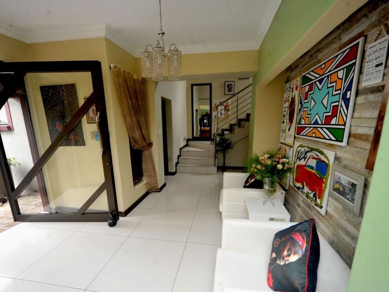 Welcoming entrance hall featuring tiled flooring, a stone feature wall, and a staircase leading to the upper level.