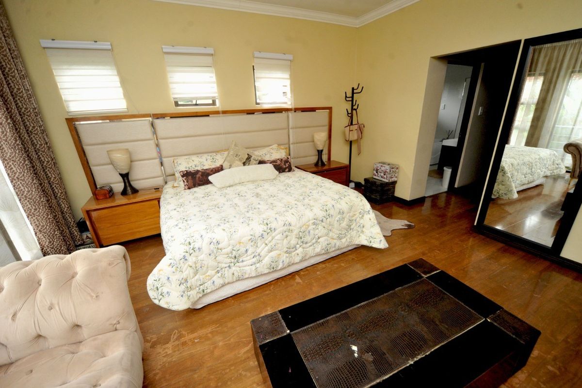 Spacious bedroom featuring hardwood flooring, crown molding, and a large built-in headboard with integrated bedside tables.