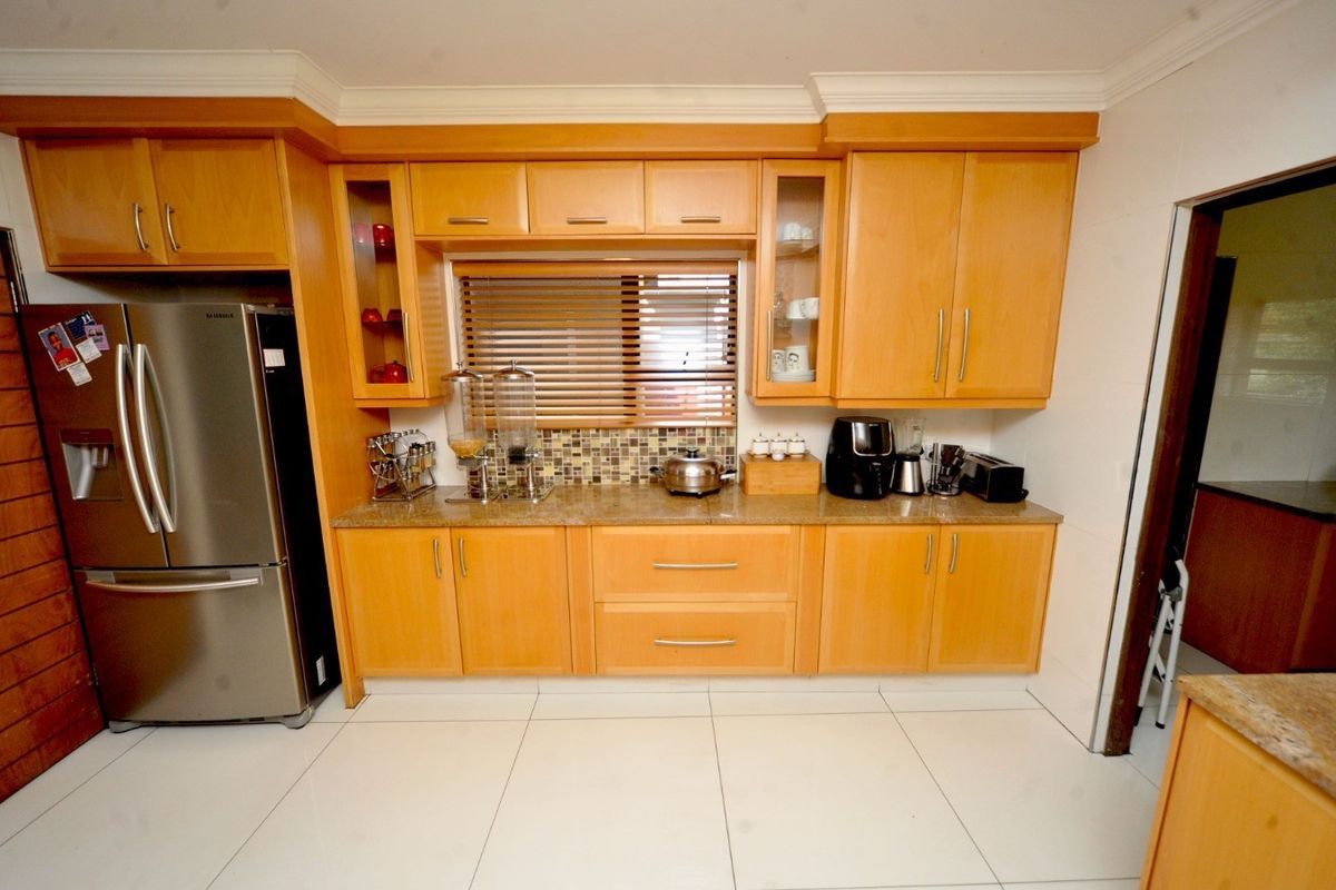 A functional kitchen featuring light wood cabinetry, granite countertops, a mosaic tile backsplash, and tiled flooring.