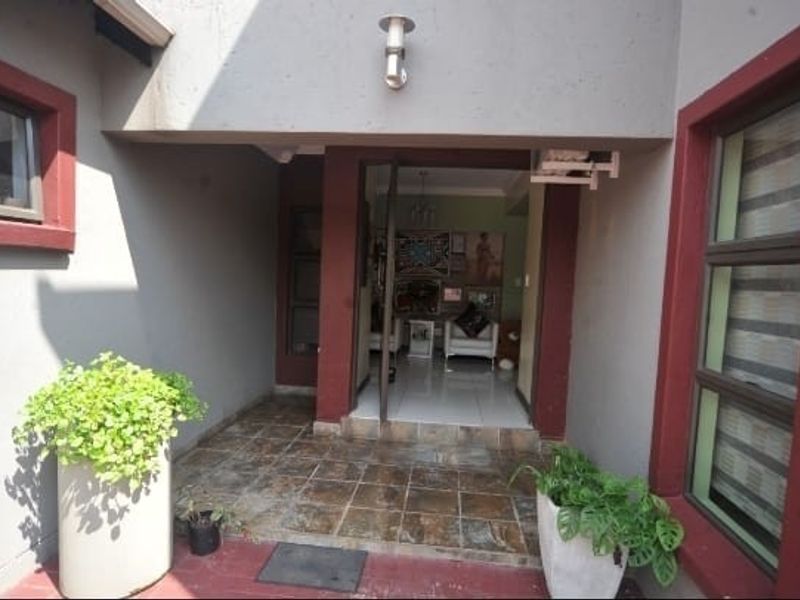 A covered entrance area featuring tiled flooring and aluminium window frames, providing a clear view into the interior living space.