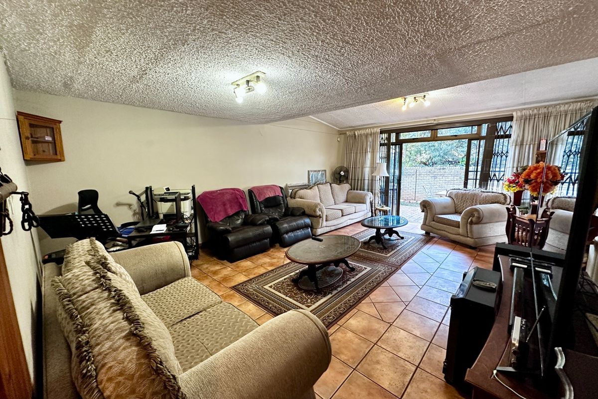 Spacious living room featuring ceramic floor tiles, textured ceiling, and large sliding glass doors providing direct access to the outdoor patio area.