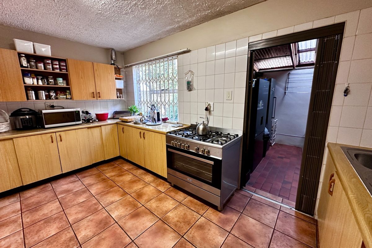 Functional kitchen featuring laminate cabinetry, tiled splashbacks, and a gas stove, with direct access to an adjacent utility area.