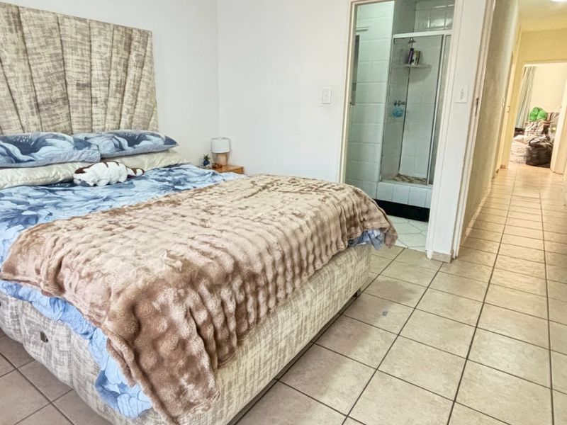 A bedroom featuring tiled flooring and direct access to an en-suite bathroom.