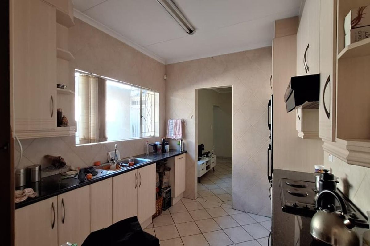 A functional kitchen featuring laminate cabinetry, granite countertops, tiled backsplash, and ceramic flooring, offering a practical layout with potential for modern updates.