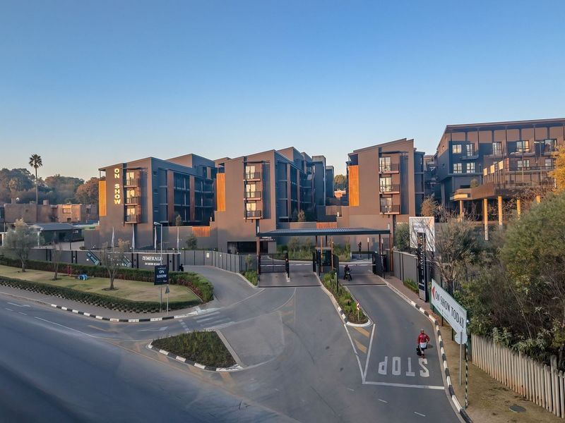Aerial view of the modern apartment complex entrance, featuring secure gated access, paved driveway, and contemporary architectural facade.