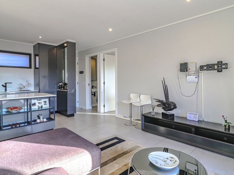 Modern open-plan living area featuring a sleek kitchen with built-in cabinetry, a central island, and neutral tiled flooring throughout.