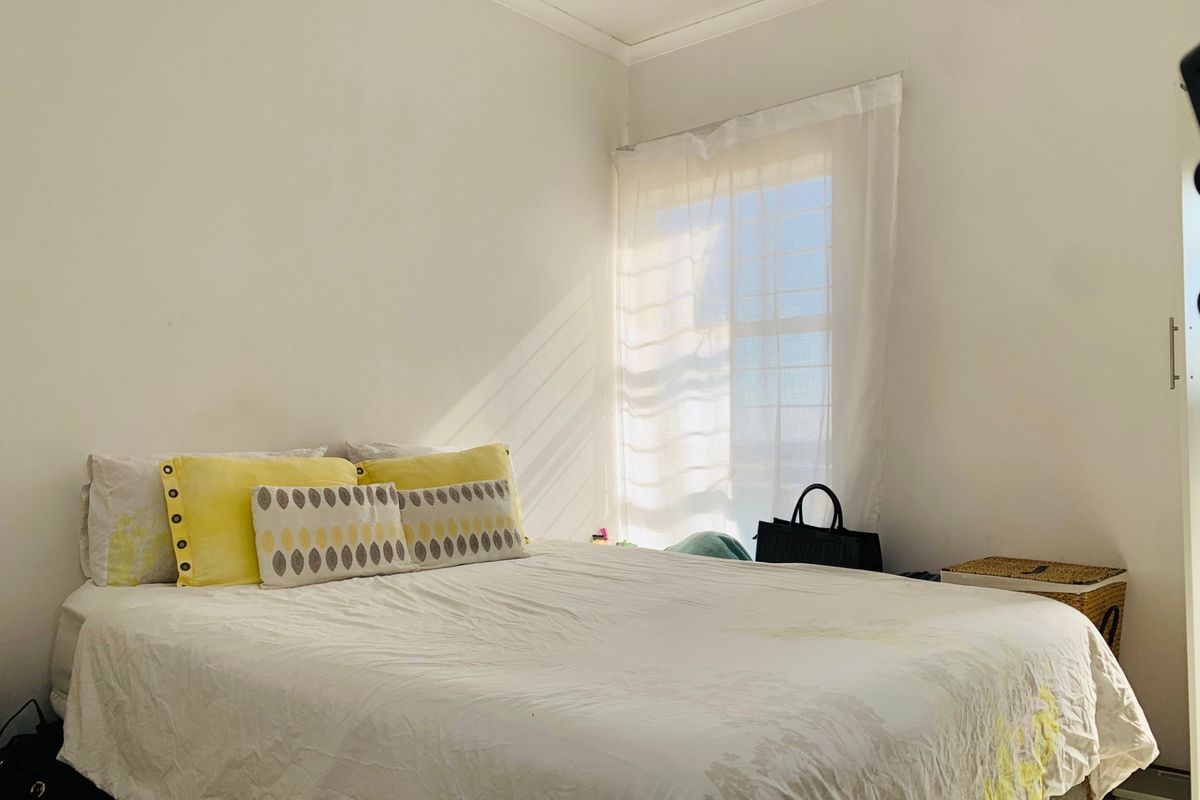 A bright bedroom featuring a window with natural light and a built-in wardrobe.