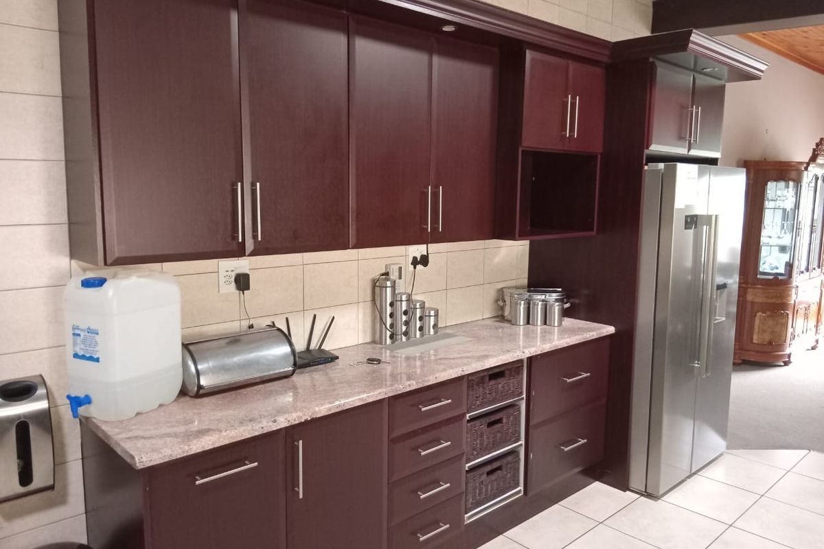 A functional kitchen featuring dark wood cabinetry, stone countertops, and a tiled backsplash, providing ample storage and workspace.