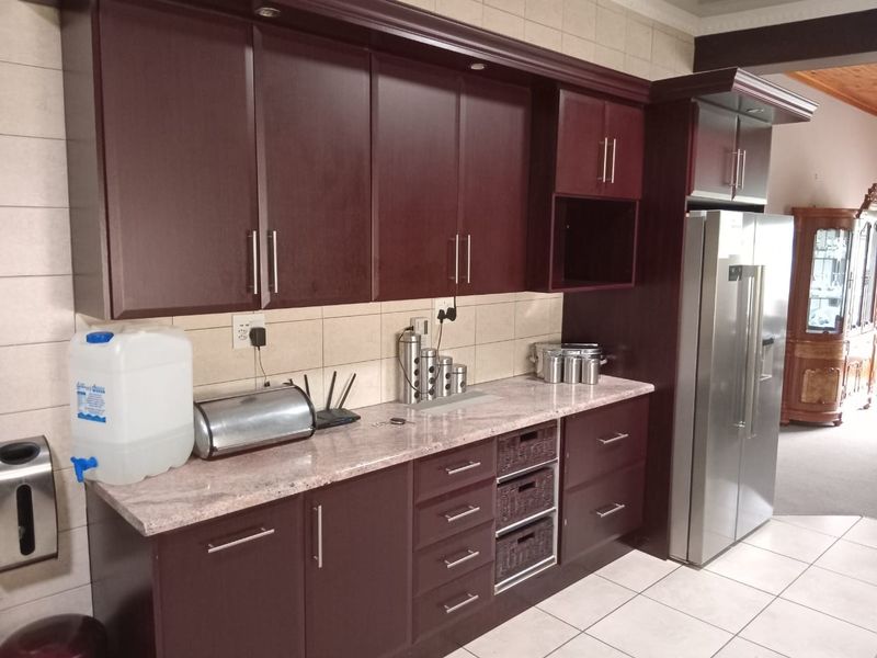 A functional kitchen featuring dark wood cabinetry, stone countertops, and a tiled backsplash, providing ample storage and workspace.