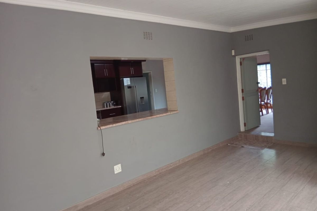 Spacious living area featuring laminate flooring, beadboard ceiling, and a convenient pass-through window connecting to the kitchen area.