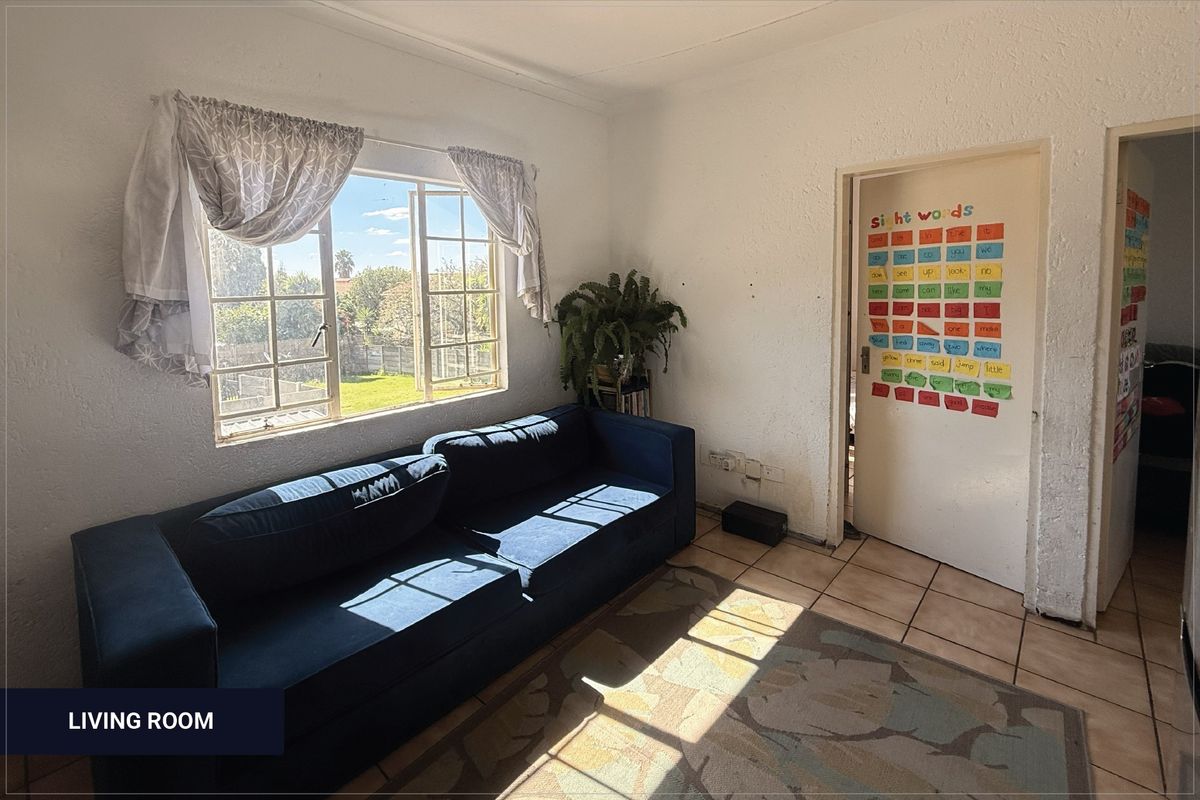 A living room featuring tiled flooring and a casement window with natural light, requiring cosmetic updates to the walls and finishes.