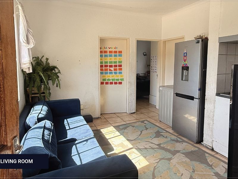 Open plan living and kitchen area featuring tiled flooring and basic built-in cabinetry, offering a functional layout for compact apartment living.