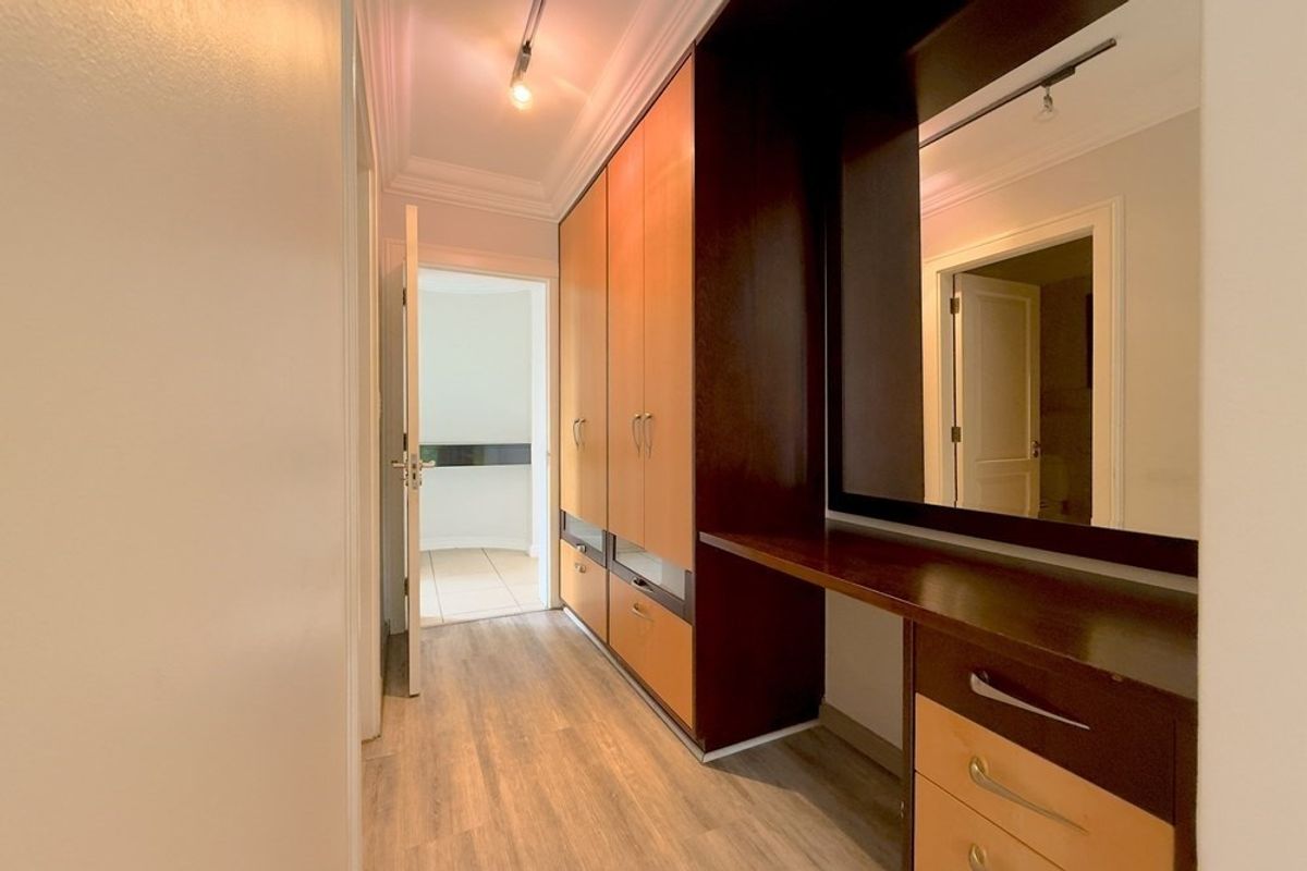 A well-maintained dressing area featuring extensive built-in cabinetry, a integrated vanity unit, and modern laminate flooring with clean finishes.