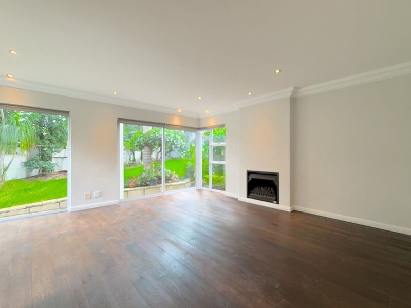 Spacious living room featuring dark hardwood flooring, a built-in fireplace, and large sliding glass doors providing views of the garden.