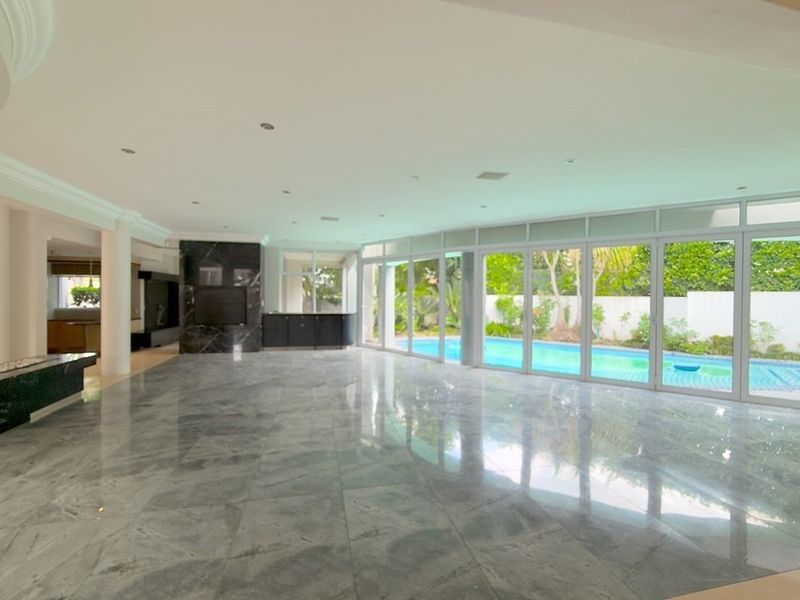 Spacious open-plan living area featuring polished marble floors, a built-in bar, fireplace, and expansive sliding glass doors overlooking the swimming pool.