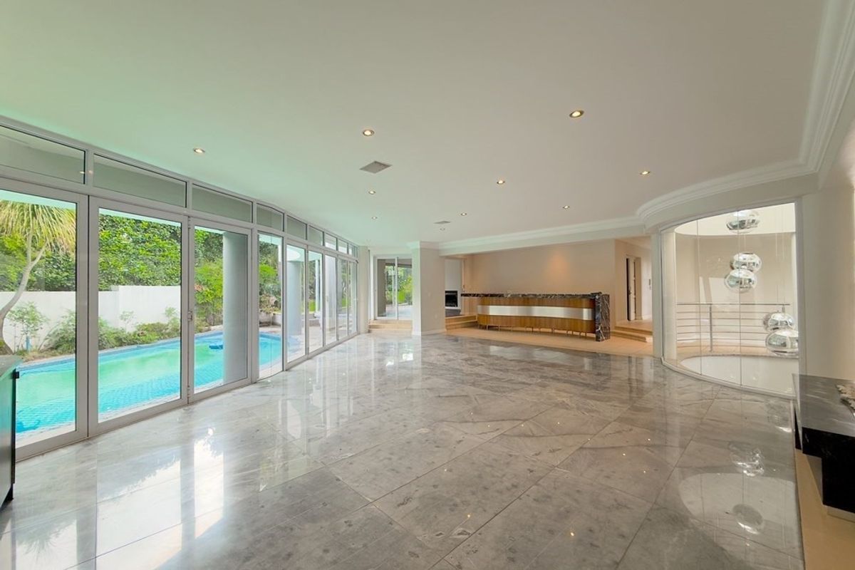 Spacious, light-filled living area featuring polished marble floors, a built-in bar, and expansive glass doors opening directly onto the pool area.