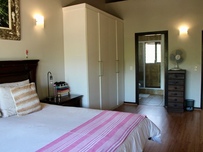 Spacious bedroom featuring laminate flooring, built-in wardrobe storage, and direct access to an en-suite bathroom.