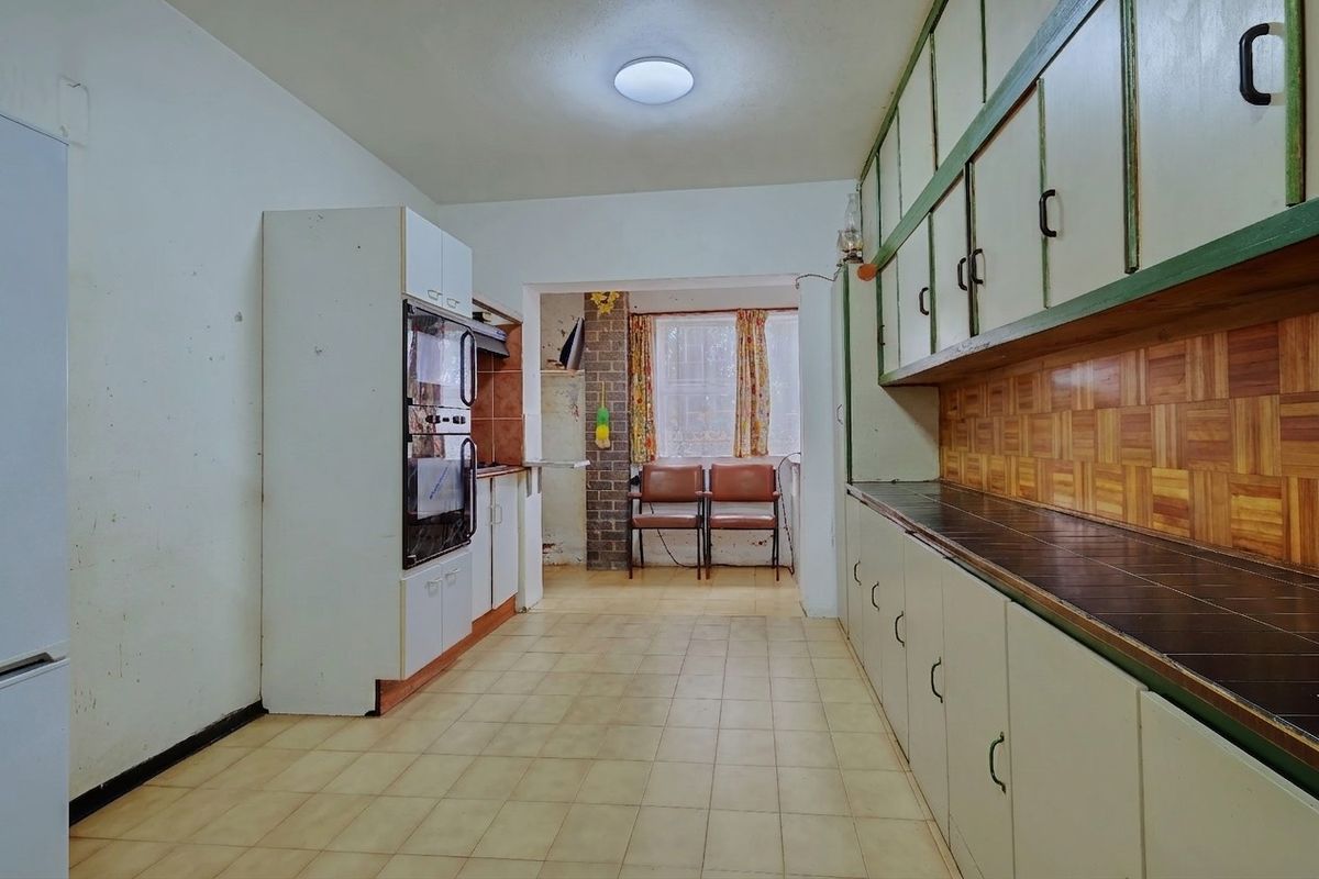 A dated kitchen featuring extensive built-in cabinetry, tiled countertops, and flooring, offering a functional layout ready for modernization and renovation.