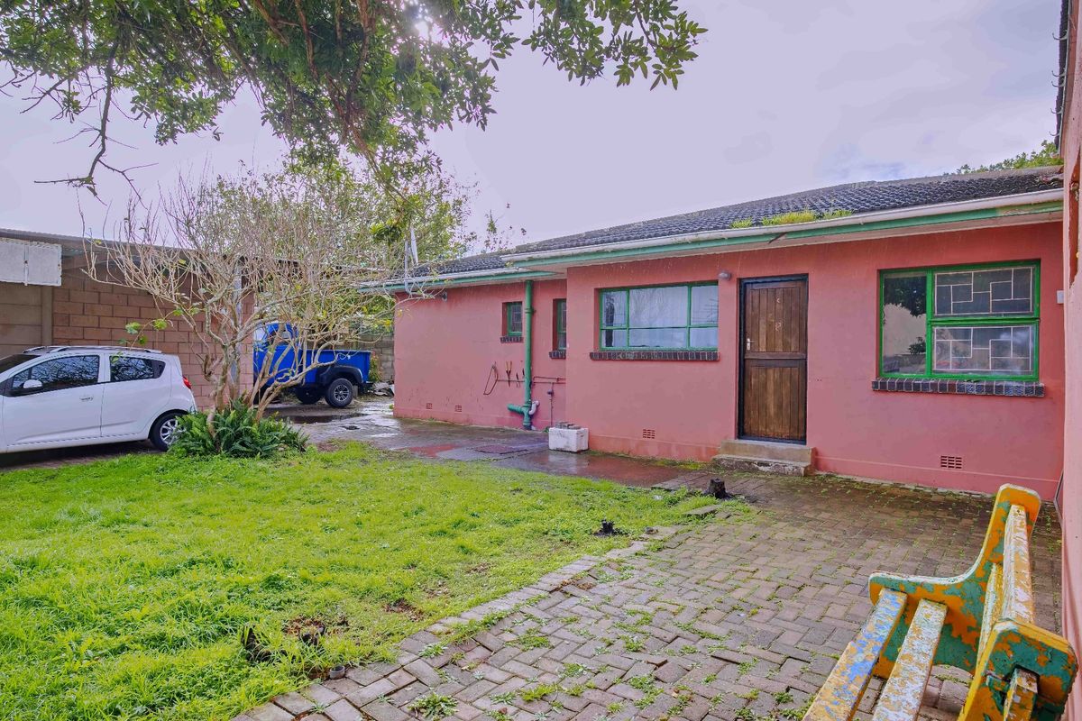 Rear exterior view of the house featuring a paved patio area, brick construction, and established garden space.