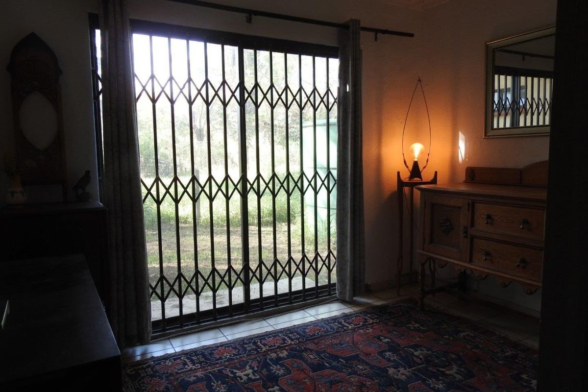 Living area featuring tiled flooring and a sliding glass door with a fitted security gate, providing access to the exterior.